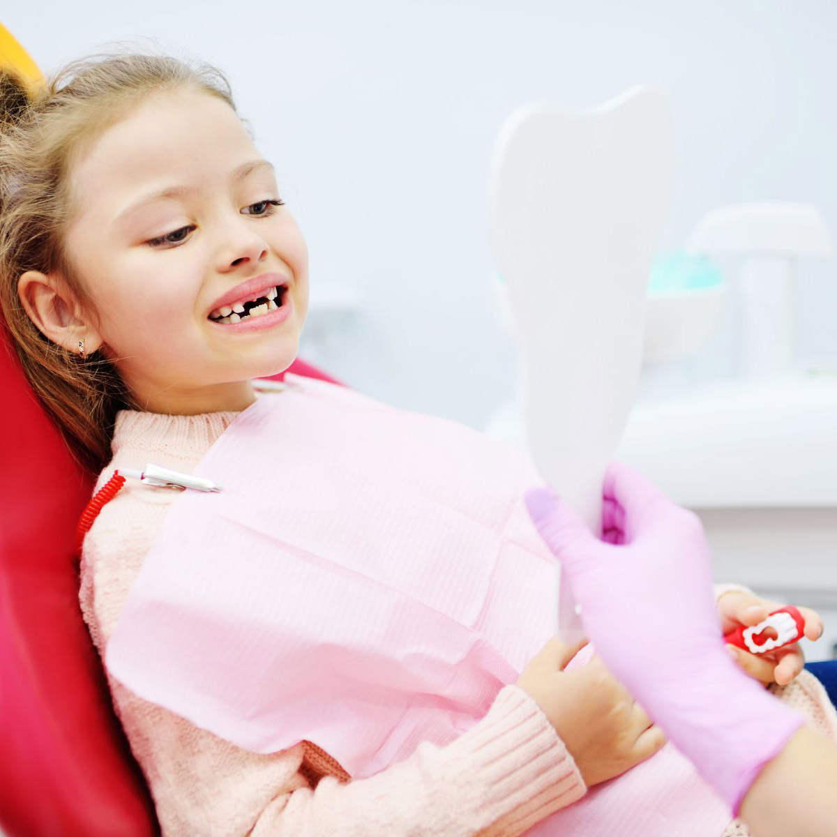 Little girl sitting on dental chair in pediatric dentists office. Early prevention, oral hygiene and milk teeth care.