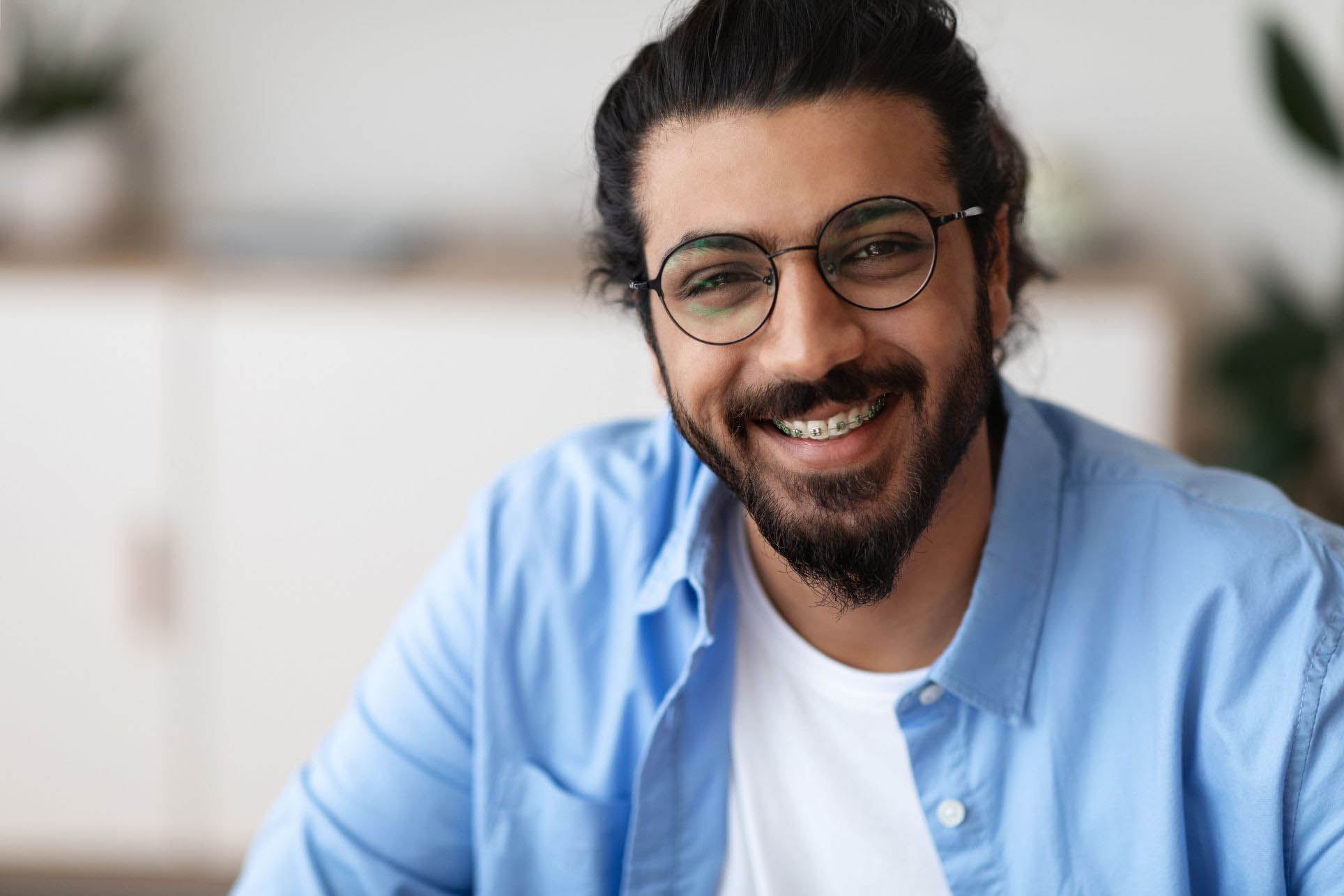 Closeup Portrait Of Positive Indian Guy With Dental Braces And Eyeglasses Smiling At Camera, Handsome Bearded Millennial Man With Brackets On Teeth Posing Indoors, Selective Focus With Copy Space